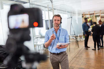 Reporter with headset in front of video camera with news