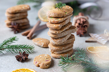 Stacked spicy butter cookies with candied fruits, cinnamon sticks and anise. Festive Christmas or New Year background with fir branches and dried oranges slices.