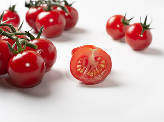 selective focus. focus on the center tomato cut in half. cherry tomatoes with green tails.