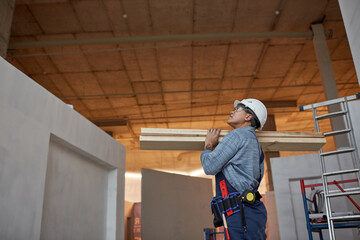 Side view portrait of modern female worker carrying wood boards while working on construction site, copy space