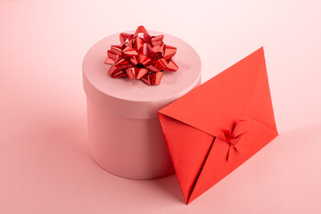 Pink round gift box and red envelope on pink background