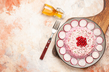 Delicious chicken salad with beet on a gray plate on wooden cutting board and olive oil fork on mixed color background