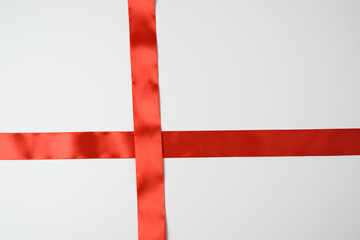Obraz premium red satin ribbon cross to cross on white background, close up