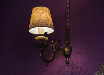 Wall lamp in a modern loft apartment. Sconce on a purple wall. Yellow lights in the shade. Evening,...