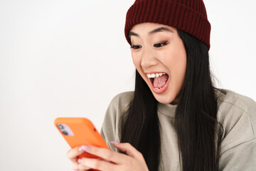 Asian excited nice girl exclaiming while using mobile phone