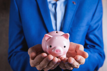 Human hand protecting a piggy bank