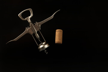 One wooden wine cork and flying corkscrew on the black background with copy space. Wine Concept....