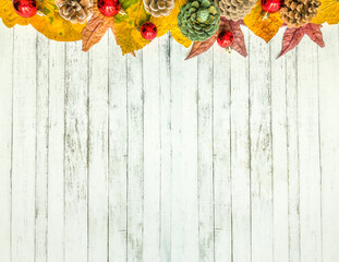 Arrangement of leaves, pine cones and christmas ornaments on a wooden surface with copy space, top view