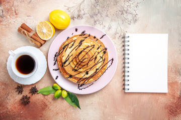 Classic pancakes with fruits cinnamon and notebook on colourful background