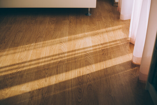Afternoon sunshine entering room through window and make pattern of light on parquet floor