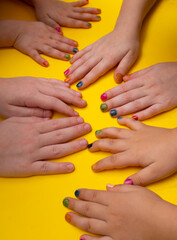 Multi-colored kids manicure on yellow background. Close up