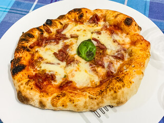 Pizza napoletana fatta in casa con sugo di pomodoro, salame piccante, mozzarella e basilico