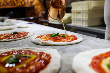 Pizza cruda napoletana con sugo di pomodoro, olio e basilico pronta per essere infornata