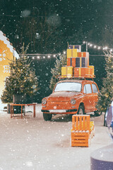 New Year's and Christmas location on the open air. Red retro car. Snowfall, lights. Christmas mood.