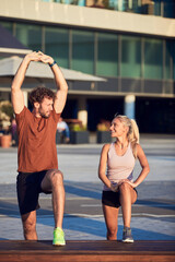 Young adult sporty couple working out outdoors in urban surroundings.