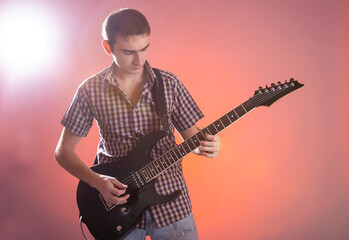 Young guitarist play music on his electric guitar with stage light.