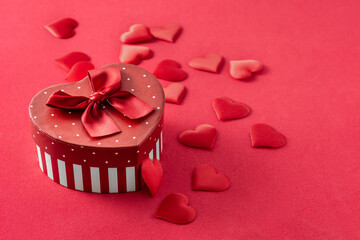 Gift box with heart shape and hearts on red background. Copy space	