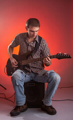 The guitarist play music with combo amplifier in beautiful red hall.  