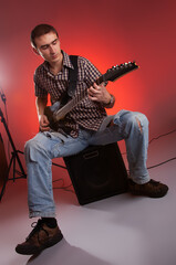 The guitarist play music with combo amplifier in beautiful red hall.  