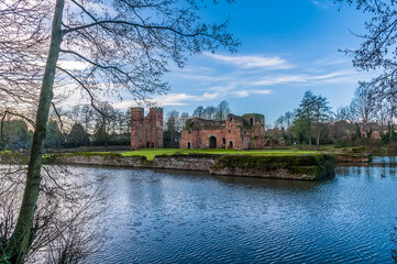 A view through the trees towards castle ruins at Kirby Muxloe, UK on a sunny day
