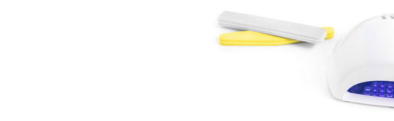 Nail LED lamp and pink file on white table. Long banner