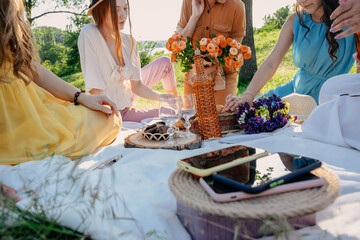 Digital Detox, time for disconnecting from electronic devices. Mobile phones on basket on picnic background. Group of young woman hanging out together on a picnic in nature at no phone zone