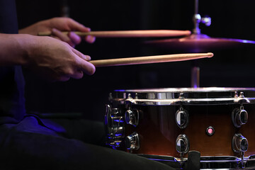 Drummer playing snare drum with sticks close up.