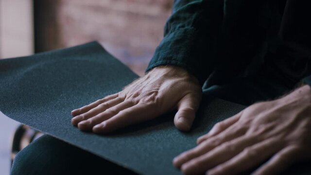Man putting new grip tape on a skateboard