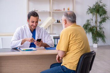 Fototapeta premium Old man visiting young male doctor