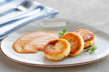 Russian cheesecakes served on plate with sauce