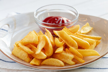 French fries potatoes in plate with sauce on wooden table