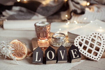 Cozy home composition with decorative word love on blurred background with bokeh.