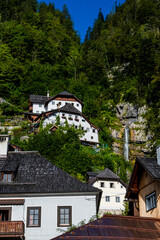 Fototapeta na wymiar Spectacular Buildings Beneath Waterfall In The Lakeside Town Hallstatt in Austria