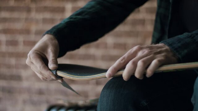 Man using sandpaper on his skateboard 