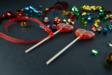 Heart-shaped sweets on a stick. Valentine's Day. Background. Candy on black background