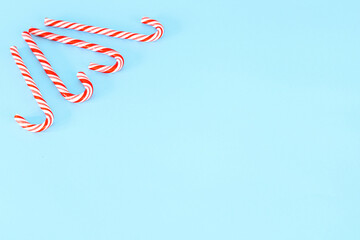 Light blue Christmas background decorated with candy canes. Place for text or Christmas greetings.
