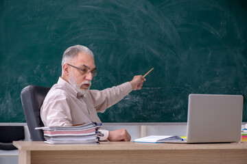 Old male teacher sitting in the classroom