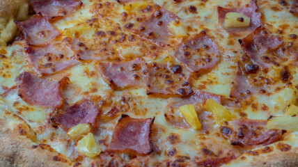 Closeup top view of delicious and crispy hawaiian pizza with cheese , bacon and pineapple.