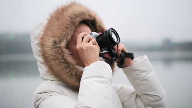 Woman in white winter coat taking photos and shooting video on a vintage camera