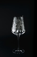 Christmas silver and red toys in a glass goblet on a black background