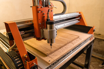 The wooden cnc machine drills a cutting Board. Automated mechanism. Movement of the drill along the specified route on the computer - obrazy, fototapety, plakaty