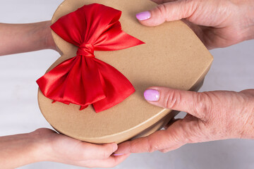 Grandmother gives her granddaughter a birthday present. The image contains only hands and a gift