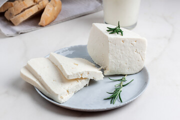 Adyghe cheese is cut into pieces on a gray plate. Soft goat cheese