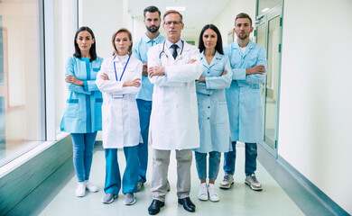 Group of successful and confident modern medical doctors are posing and looking on the camera at the hospital corridor