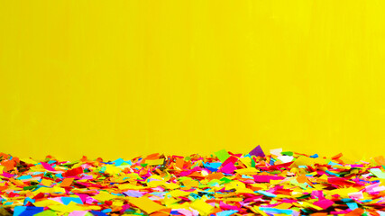 Fototapeta na wymiar Close-up of a ground full of confetti with a yellow background.