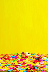Close-up of a ground full of confetti with a yellow background.