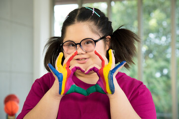 Portrait of Asian disabled child kid complex genetic disorders down syndrome girl with colorful painted hands