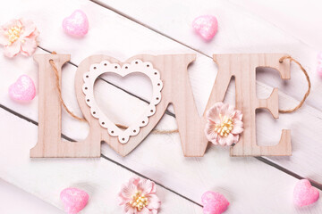 Wooden background with the word love, pink hearts and flowers