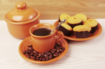 Cup of coffee and pastry muffins on a wooden table.
