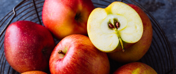 Fresh red apples on a dark background. An apple is cut in half